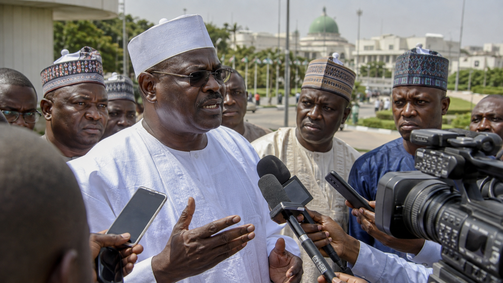 AI-generated editorial illustration of Senator Ali Ndume addressing reporters outside the National Assembly